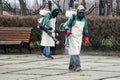 Workers in chemical protection suits decontaminate a city street or park during quarantine and a pandemic. Antiviral Fluid Spray