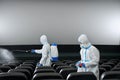 Workers cleaning cinema hall with disinfectants.