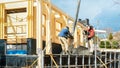 Workers concrete the retaining wall and foundation for the terrace using formwork and scaffolding. Construction site of a wooden Royalty Free Stock Photo