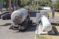 Workers connect hoses for transferring autogas from a car transporter to a gas filling station Royalty Free Stock Photo