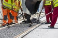 Workers construct asphalt road and railroad lines Royalty Free Stock Photo