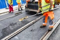 Workers construct asphalt road and railroad lines Royalty Free Stock Photo