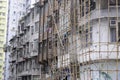 Workers on construction site building bamboo scaffolding on house facade in Hong Kong