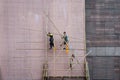 Workers on construction site building bamboo scaffolding on house facade in Hong Kong