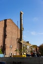 Workers at a construction site in the city center. Special equipment for piling works near the side facade of the old house