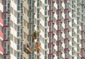 Workers in a cradle on a background of enormous house Royalty Free Stock Photo