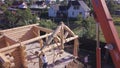 Workers with crane lift wooden structure of house. Clip. Top view of process of installing facade of wooden roof with