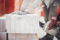 Workers cutting autoclaved aerated concrete block with chainsaw closeup. Builders cutting white blocks for masonry installation. Royalty Free Stock Photo