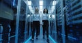 Workers in a data center walking between rows of server racks