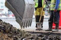 Workers deepen the road pit with an excavator for further repairs and asphalting.