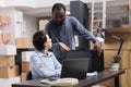 Workers discussing about metallic box while checking transportation logistics for package delivery on laptop Royalty Free Stock Photo