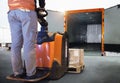 Workers Driving Forklift Pallet Jack Unloading Cargo Pallets into Cargo Container Truck. Loading Dock. Shipping Warehouse Logistic Royalty Free Stock Photo