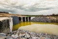 Workers are engaging in construction near a large water pool at a site where earth and materials are being prepared under a cloudy Royalty Free Stock Photo