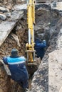 Workers excavate the pit with an excavator. Road repair.