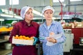 Workers of fruit storage and sorting facility talking about work process standing near the conveyor line and tangerine