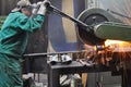 Workers in a foundry grind castings with a grinding machine - He