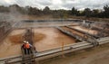 Workers on a gangway look in the pulping ponds at a paper manufacturers