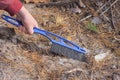 a workers hand with a black blue plastic brush sweeps garbage