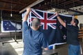 Workers hang a print of the National New Zealand flag