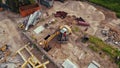 Workers with helmets working at a construction site, one operating a yellow digger. Royalty Free Stock Photo