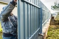 Workers install of gray fence from metal profile