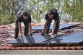 Workers installing alternative energy photovoltaic solar panels on roof