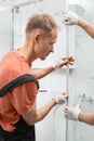 Workers are installing a gasket seal on the glass door of the shower enclosure