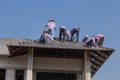 Workers installing roof tiles for home building