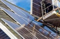 Workers installing solar panels on private home hexagonal roof felt on sunny day  blue sky. Royalty Free Stock Photo