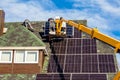 Workers installing solar panels on private home hexagonal roof felt on sunny day  blue sky. Royalty Free Stock Photo