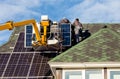 Workers installing solar panels on private home hexagonal roof felt on sunny day  blue sky. Royalty Free Stock Photo