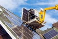 Workers installing solar panels on private home hexagonal roof felt on sunny day  blue sky. Royalty Free Stock Photo