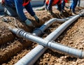 Workers lay power and data cables in concrete trough below future road surface. Royalty Free Stock Photo