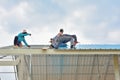 Workers are laying roof on steel frame. Royalty Free Stock Photo
