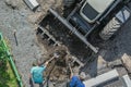 Workers load soil into excavator bucket during road construction