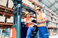 Workers in logistics warehouse at forklift checking list Royalty Free Stock Photo