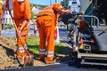 Workers make blacktop. New asphalt is laid over the old asphalt at the intersection, filling in several potholes in the