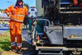 Workers make blacktop. New asphalt is laid over the old asphalt at the intersection, filling in several potholes in the