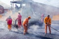 Workers making asphalt with shovels at road