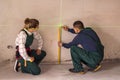Workers measuring walls with laser level tool