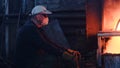 Workers at metallurgical plant working with hot metal. Stock footage. Workers in uniforms and helmets work with Royalty Free Stock Photo