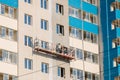 Workers on a mobile platform are plastering the windows of the house with