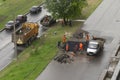 Workers in orange overalls doing road work on laying of asphalt