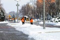 Workers in orange vests and a tractor clean the city street from fresh snow in the winter . Dnipro city Royalty Free Stock Photo