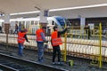 Workers paint a fence with yellow paint