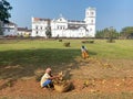 Workers picking dry leaves and sweeping the gardens around the ancient Portuguese era Se Cathedral