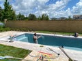 Workers from a pool finishing company spraying plaster finish on the interior of a swimming pool