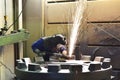 Workers in protective equipment in a foundry work on a casting with a grinding machine at the workplace