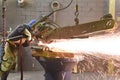 Workers in protective equipment in a foundry work on a casting with a grinding machine at the workplace