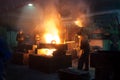 Workers in protective gear operate in a foundry, handling molten metal with machinery. Industrial manufacturing process Royalty Free Stock Photo